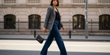 Stylish woman in dark wash wide-leg jeans and blazer, embodying 2025 celebrity denim trend.